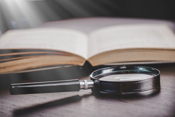 Handbücher zum Nachschlagen Lupe liegt vor einem Buch