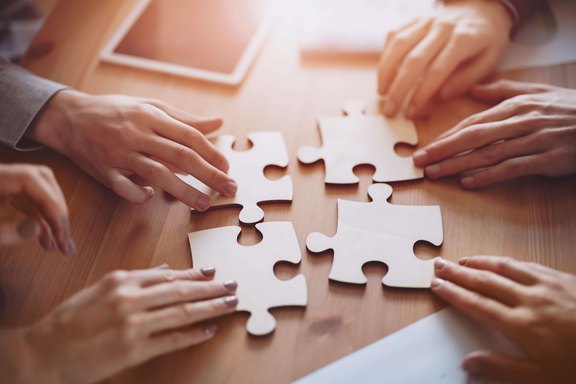 Teamwork Puzzle Vier Personen bei einem Puzzle