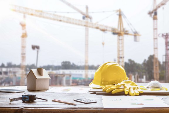 Bauwerkzeug Tisch mit einem Gebäudemodell aus Holz, einem Bauhelm, Pläne und weitere Utensilien